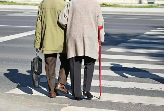 Old couple walks on the pedestrian crossing