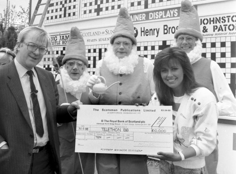 The then Scotsman newspaper editor Magnus Linklater presents Debbie Greenwood with a cheque for Telethon 88 at Glasgow Garden Festival in May 1988. Three men dressed as garden gnomes look on.