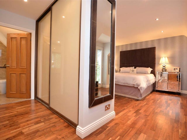 There are five bedrooms in total including this spacious master suite, which features walnut wood flooring, a dressing room area and en-suite bathroom, with a walk-in shower cubicle.