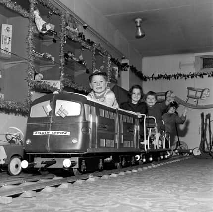 Children play on the model of the Golden Arrow engine in Edinburgh's Jenners department store, with Christmas decorations in the background, in 1965.