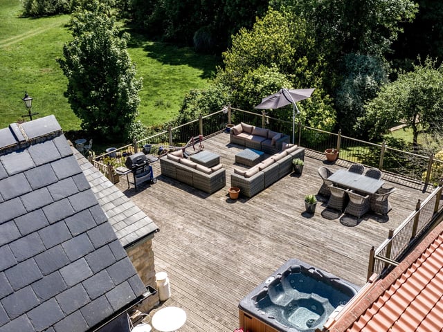 The large raised patio, on top of the garage/worksop, has several seating areas and room for a hot tub.