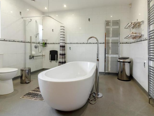 The en suite bathroom is as unique as its is spacious. A white four-piece suite, with chrome fittings, comprises a large Royce Morgan bathtub, a walk-in shower enclosure with screen, vanity hand wash basin and WC. Add  storage cupboards, heated towel-rails, six ceiling spotlights, an extractor fan, tiled walls, shelves and a built-in wardrobe with double hanging-rail and you have bathroom luxury!