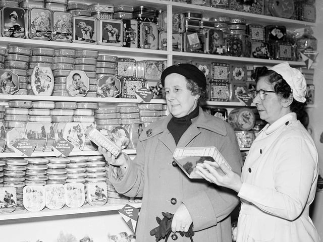 Two shoppers selecting from a range of tins of toffees in in 1958.