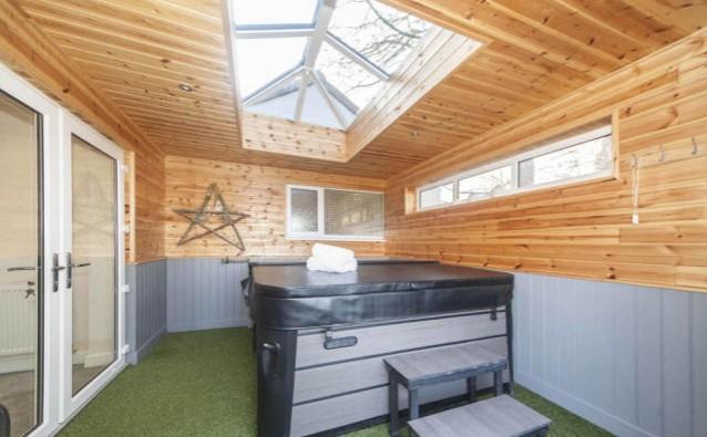 The hot tub room has a huge skylight and is clad in Scandinavian style wood, with spotlights and has light flooding in from several sources, artificial turf and access to the back garden through double doors.
