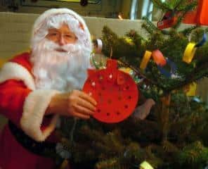 Santa Alan helps decorate a Christmas tree