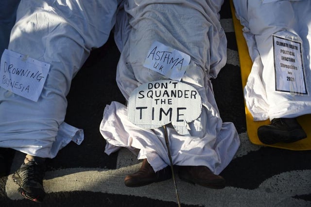 Activists from the climate change group Extinction Rebellion (XR) pretend to be dead under white sheets as they hold a "Remember climate death"