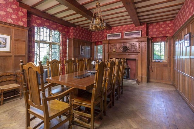 The formal dining room features an oak panelled room with herringbone parquet floor and a beamed ceiling, with the open hearth fireplace serving as the focal point.