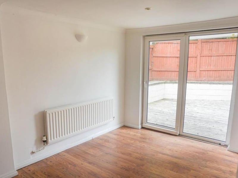 Airy spacious neutrally decorated room with wall mounted lights and ceiling spotlights, low maintenance flooring and patio doors opening onto the garden and patio decking providing a lovely social space to bring the outside in