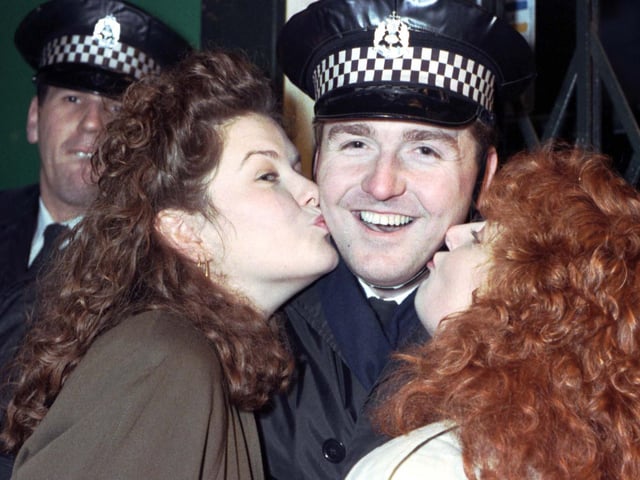 Two women kissing a police officer at the Tron kirk in Edinburgh on Hogmanay 1990.