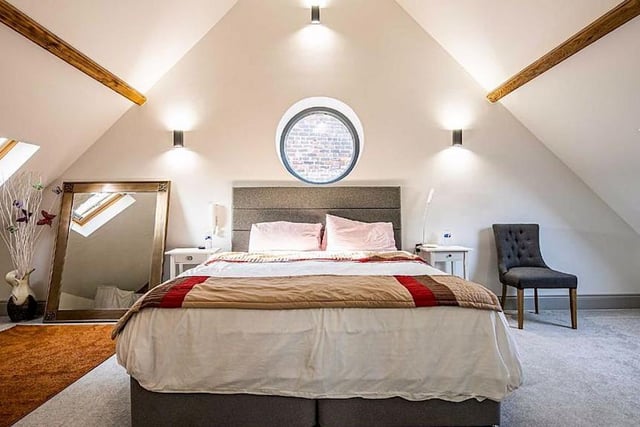 On the first floor, there is a master bedroom with original features, including a circular timber double glazed window and exposed beams. It leads through to an en-suite bathroom with a separate walk-in shower. There are two further double bedrooms that each have built-in Sharps wardrobes, and Velux windows.