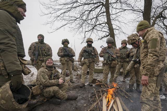 Ukrainian servicemen share jokes while sitting around a fire during an exercise in a Joint Forces Operation controlled area in the Donetsk region, eastern Ukraine, Thursday, Feb. 10, 2022. A peace agreement for the separatist conflict in eastern Ukraine that has never quite ended is back in the spotlight amid a Russian military buildup near the country's borders and rising tensions about whether Moscow will invade.(AP Photo/Vadim Ghirda)