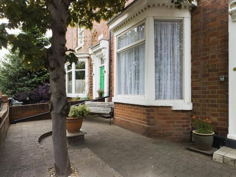 Front garden - wall enclosed with wrought iron access gate and railings, block paved with mature tree.