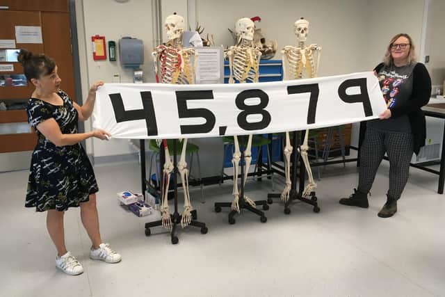PhD Bronwen Stone (left) and lab technician and PhD student Yvette Marks (right) hold up banner showing the number of people who have signed a petition in support of the archaeology department.