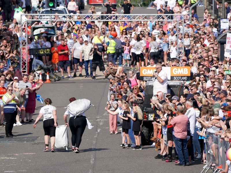 Competitors in the Women's Race take part in the Scottish Coal Carrying Championships through the streets of Kelty in Fife.  Picture date: Saturday August 28, 2021. PA Photo. The annual event is one of only two Coal Races in the world and the men's race requires participants to carry a 50-kilo bag of coal and the women's race requires a 25-kilo bag of coal to be carried over 1000 metres through the village. Photo credit should read: Jane Barlow/PA Wire 