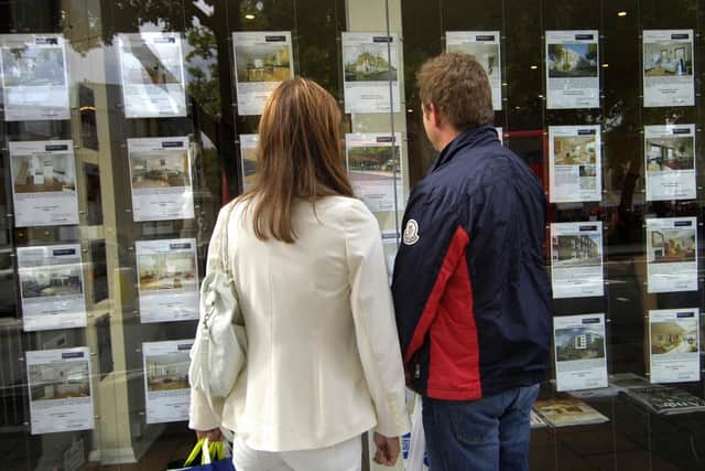First time buyers standing outside an estate agent's window.