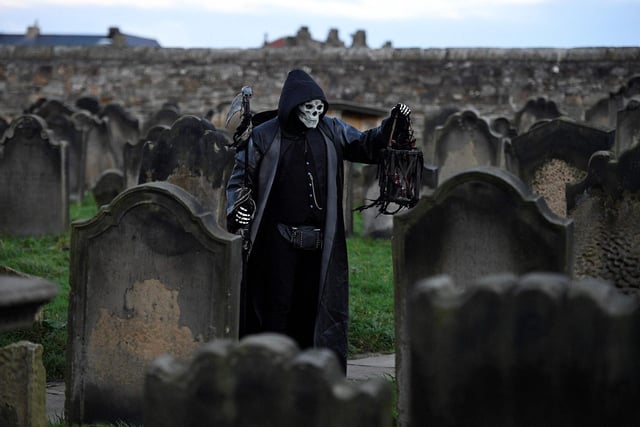 TOPSHOT - A participant in costume stands amongst gravestones at St Mary the Virgin's church during the biannual 'Whitby Goth Weekend' festival in Whitby, northern England, on October 31, 2021. - The festival brings together thousands of goths and alternative lifestyle fans from the UK and around the world for a weekend of music, dancing and shopping. (Photo by Oli SCARFF / AFP) (Photo by OLI SCARFF/AFP via Getty Images)