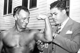 World heavyweight champion Joe Louis (1914 - 1981) admires the flexed bicep of Charles Atlas, considered by some to be the world's most perfectly developed man, at Madame Bey's Camp in Summit, New Jersey.   (Photo by Keystone/Getty Images)
