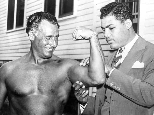 World heavyweight champion Joe Louis (1914 - 1981) admires the flexed bicep of Charles Atlas, considered by some to be the world's most perfectly developed man, at Madame Bey's Camp in Summit, New Jersey.   (Photo by Keystone/Getty Images)