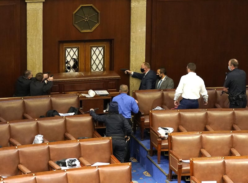 U.S. Capitol police officers point their guns at a door that was vandalized in the House Chamber during a joint session of Congress