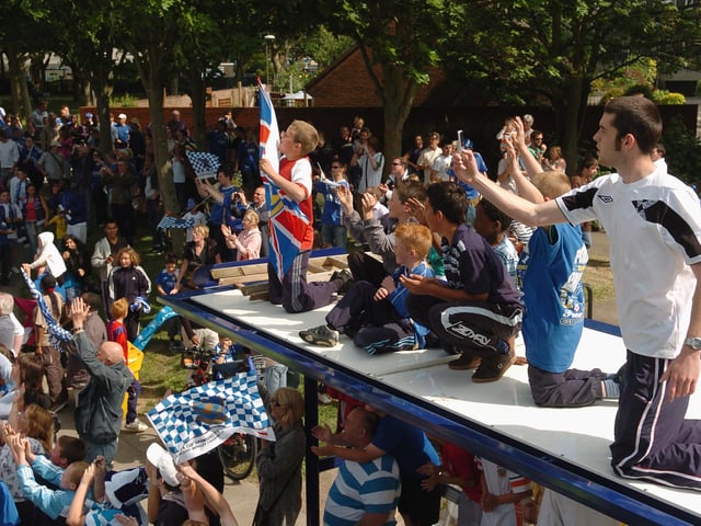 Children up high on the roof of a bus stop to see the Pompey parade bus pass by and capture the historic moment. Picture: Malcolm Wells 082235-126
