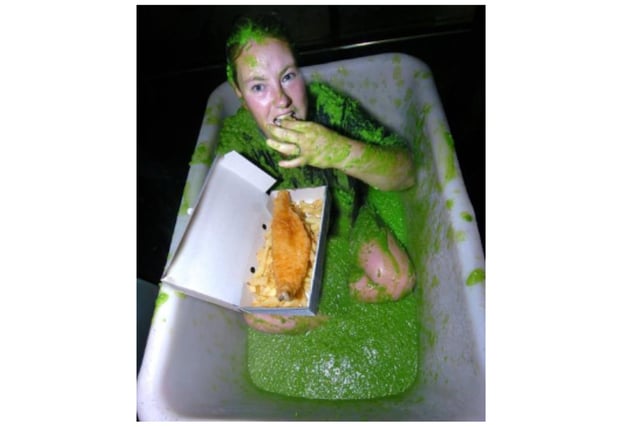 Michelle Lewis tucks into some fish and chips while sitting in a bath of mushy peas at Kosy's Plaice in Askern, Doncaster, to raise money for Children In Need