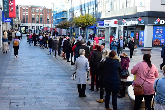 Shoppers stand in line to visit the fashion shop