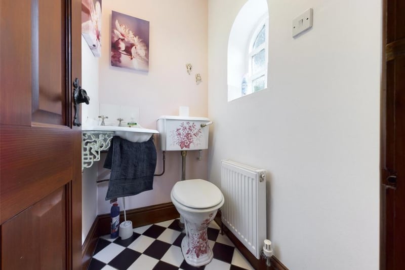 Period style suite comprising low level WC and wall mounted corner hand wash basin with tiled splash-back.