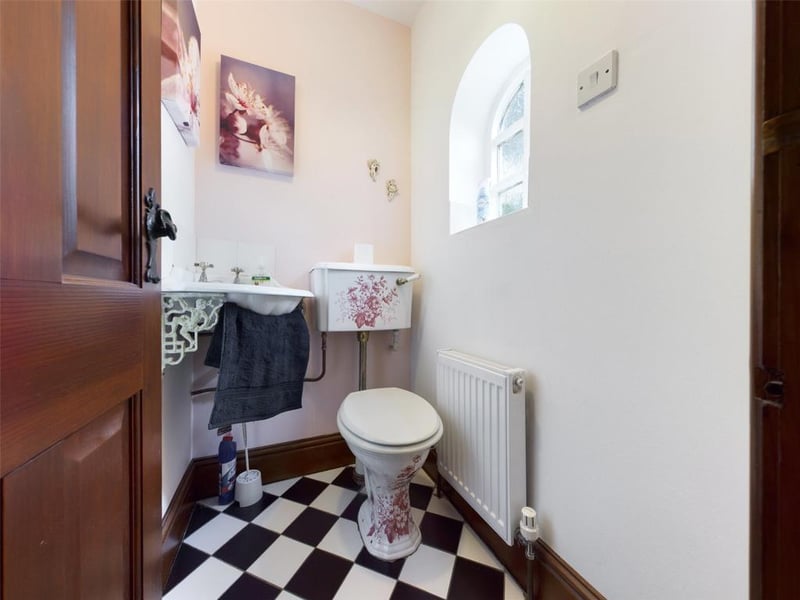 Period style suite comprising low level WC and wall mounted corner hand wash basin with tiled splash-back.