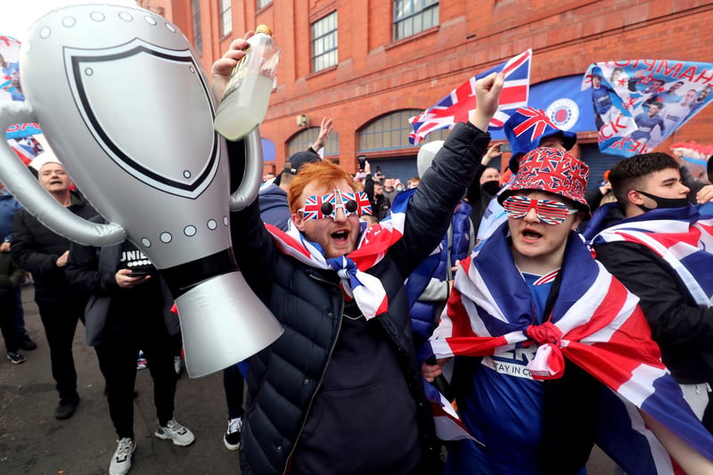 A Rangers fan holds up an inflatable trophy as he celebrates outside of the Ibrox Stadium after Rangers win the Scottish Premiership title.