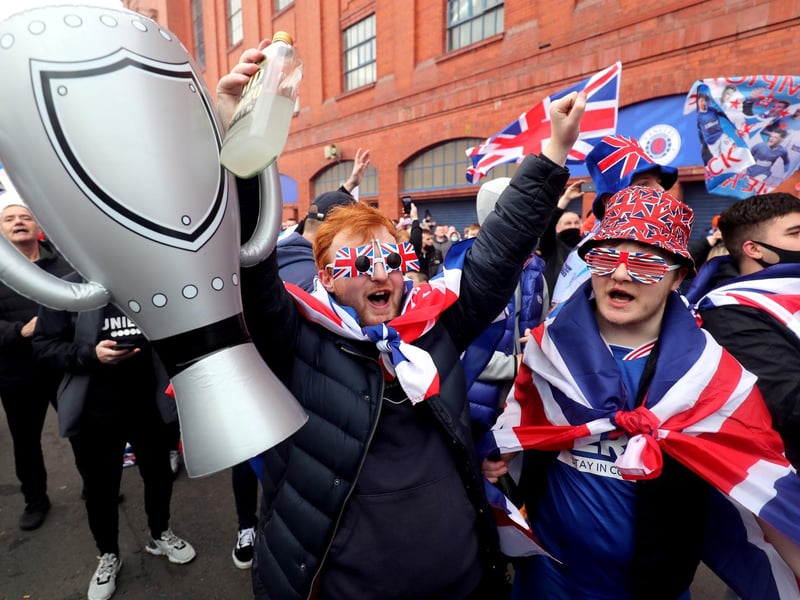 A Rangers fan holds up an inflatable trophy as he celebrates outside of the Ibrox Stadium after Rangers win the Scottish Premiership title.