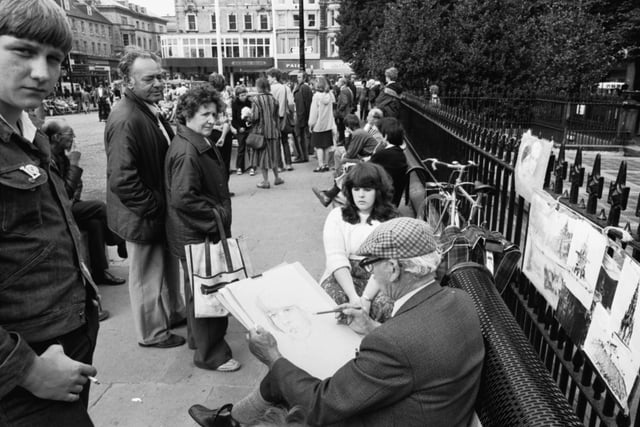 A street artist sketches a woman's face as by-passers look on, at the pedestrian area at the Mound, Edinburgh Festival, September 1981