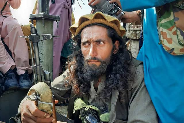 A Taliban fighter sits over a vehicle on a street in Laghman province