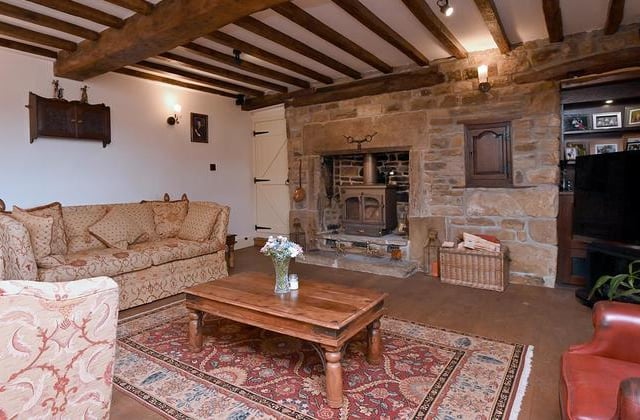 The living room has beamed ceilings, oak latched doors and feature exposed stone walls.