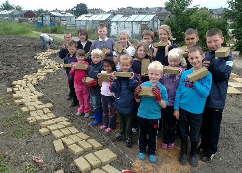 Pictured on the allotments next to the Intake Primary school, Mansfield Road, Sheffield, where pupils and parents are creating a garden with the theme of The Wizard of Oz. Seen are children with their yellow bricks laying the yellow brick road (June 2004)