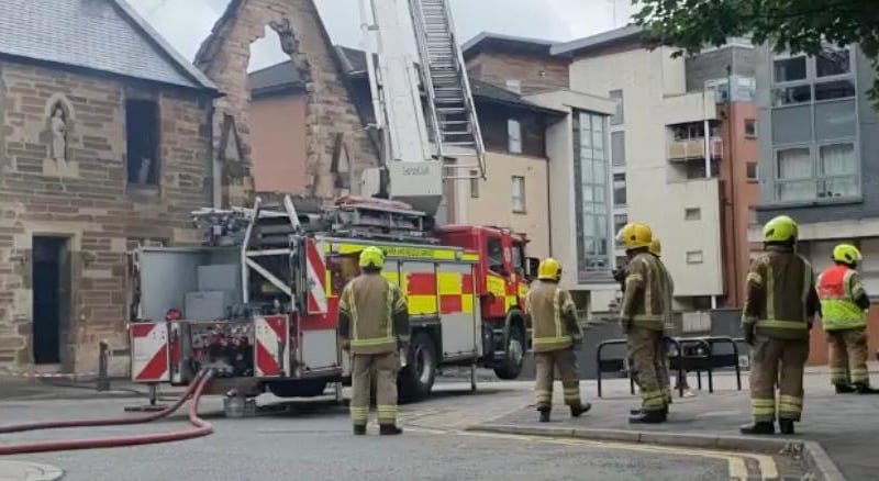 Another shot showing the extent of the damage to the front of St Simon's Church as firefighters gathered around the scene after extinguishing most of the flames.