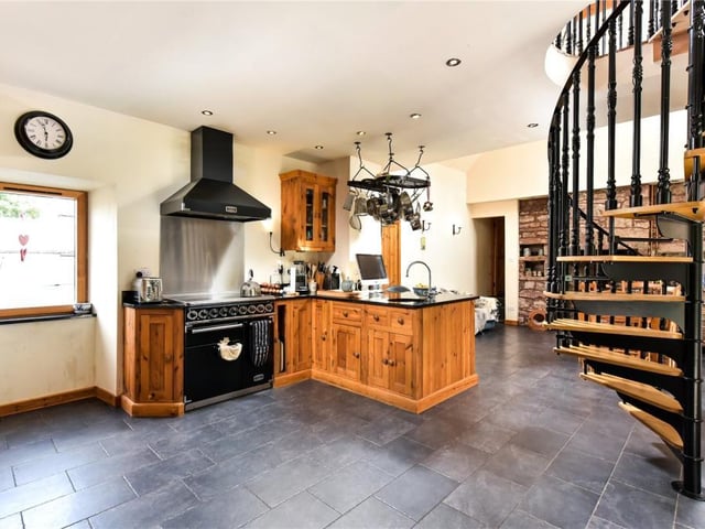 The kitchen features fitted base and wall units which house an integrated dishwasher, Falcon range cooker with induction hob, two sinks and ample storage.