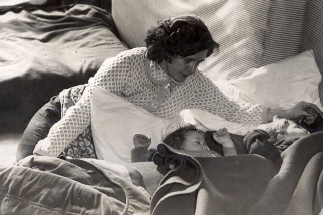 Mrs Josephine Ellar looks over her two sleeping children, Anthony aged two and John aged one, at the Hurlfield Secondary Boys School which has been turned into an emergency centre, after she had evacuated her gale damaged home in Herrington Avenue, February 1962.
