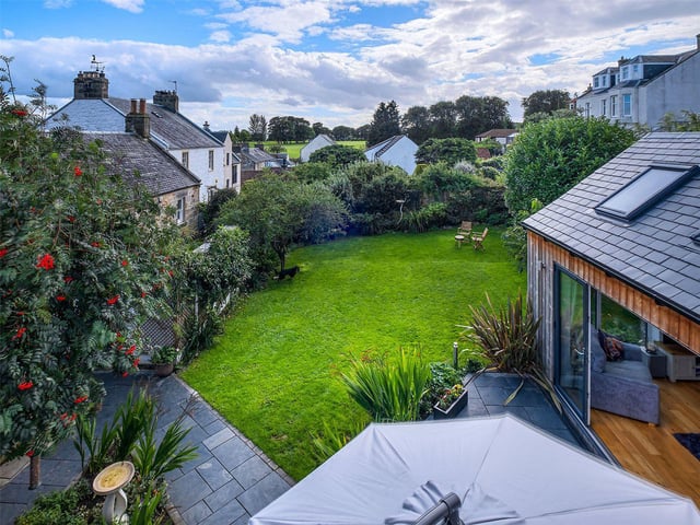 The property has an enclosed garden with a mix of plants, trees and shrubs and a sheltered paved terrace to the front of the house.