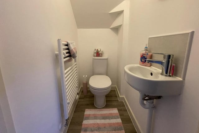 The downstairs loo features a low-flush WC, a wall-mounted sink with mixer tap, and a heated towel-rail.