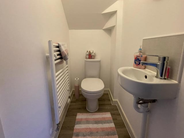 The downstairs loo features a low-flush WC, a wall-mounted sink with mixer tap, and a heated towel-rail.