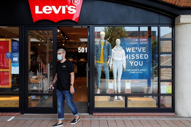 A retail worker wearing PPE directs customers waiting to enter a Levi's clothes store at Gunwharf Quays.