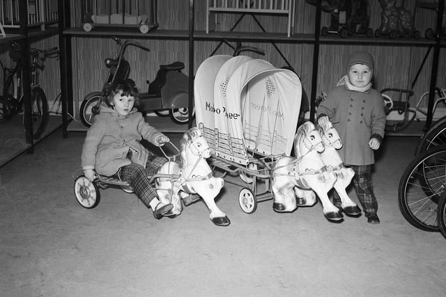 A brother and sister like the look of toy ponies and a covered wagon in Edinburgh in December 1959.
