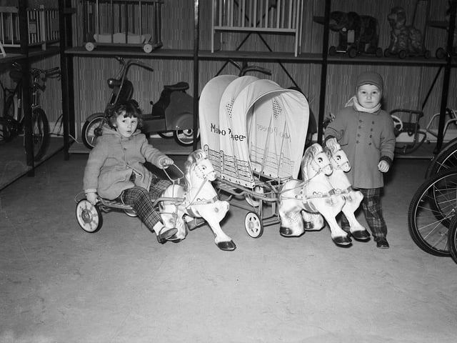 A brother and sister like the look of toy ponies and a covered wagon in Edinburgh in December 1959.