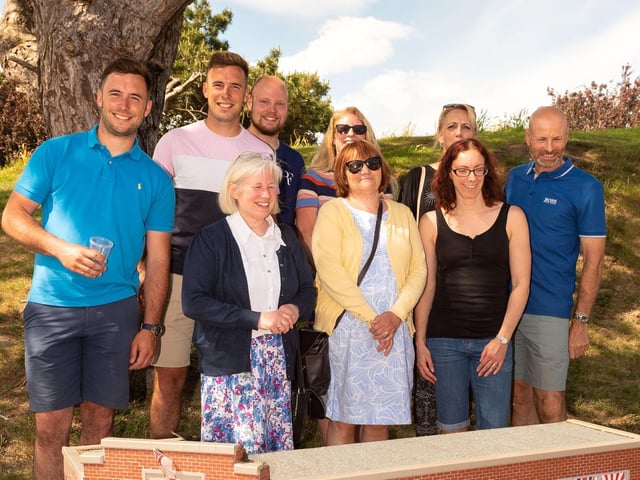 The U-Need-Us team at the unveiling of a miniature version of their shop at Southsea Model Village.