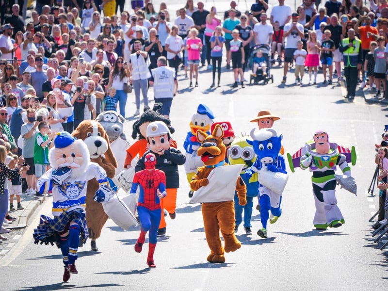 Competitors in the Mascot Race take part in the Scottish Coal Carrying Championships through the streets of Kelty in Fife. Picture date: Saturday August 28, 2021. PA Photo. The annual event is one of only two Coal Races in the world and the men's race requires participants to carry a 50-kilo bag of coal and the women's race requires a 25-kilo bag of coal to be carried over 1000 metres through the village. Photo credit should read: Jane Barlow/PA Wire