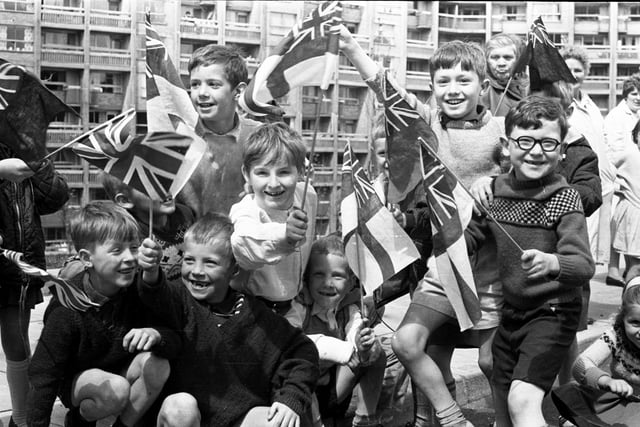 Children wave flags at Hyde Park flats as they wait for a glimpse of the Queen Mother, June 23, 1966