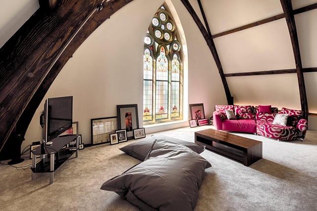 Leading from the main living space is a further cosy sitting room which sits tucked under a grand beamed archway, with three beautiful stained glass windows bringing in plenty of light.