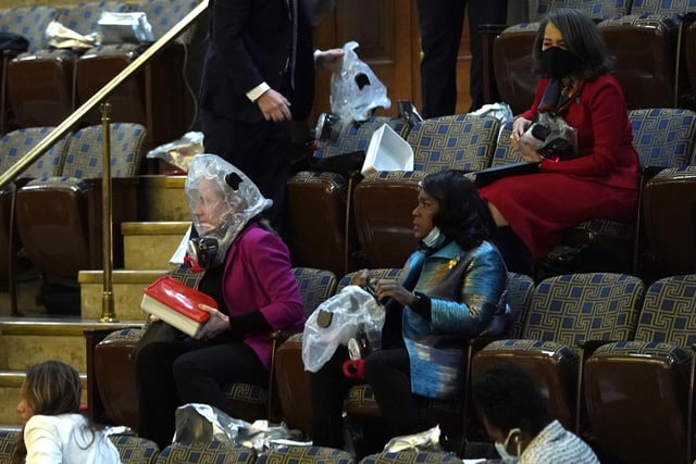 People wear plastic respirators as they are evacuated from the House Chamber as protesters attempt to enter the chamber