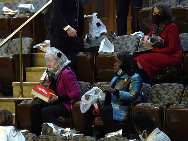 People wear plastic respirators as they are evacuated from the House Chamber as protesters attempt to enter the chamber