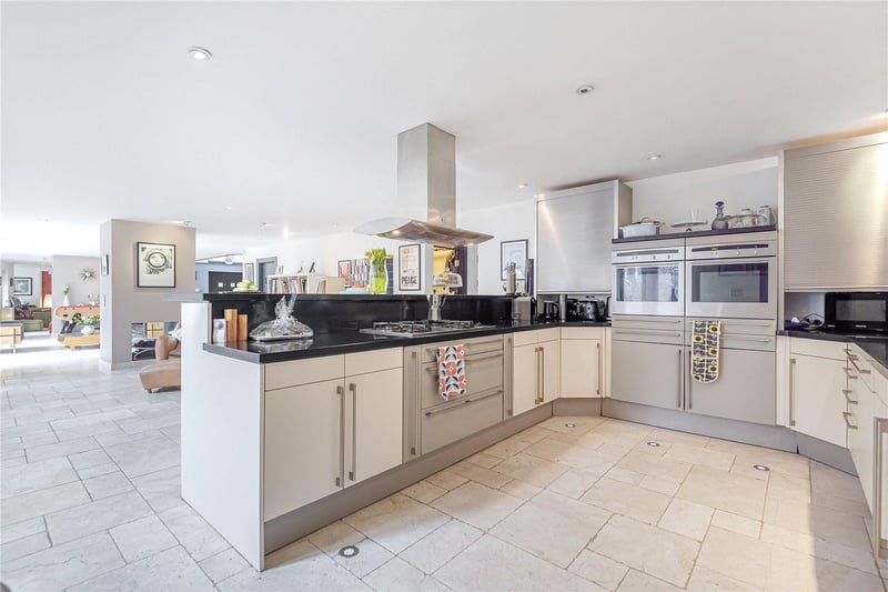The kitchen is fitted with cream and grey units with granite work surfaces, integrated appliances and a breakfast bar with ample storage below.